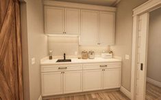 an empty kitchen with white cabinets and wood flooring is pictured in this image from the doorway