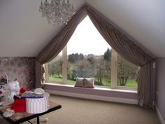 a room with a large window and a chandelier hanging from it's ceiling