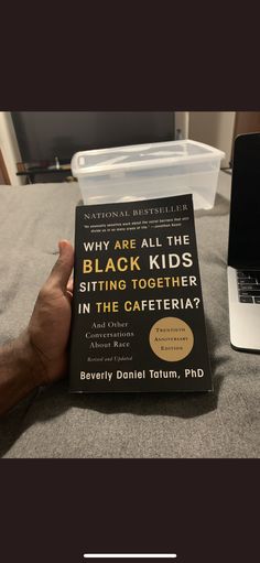 a book sitting on top of a bed next to a laptop and a person's hand