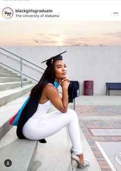 a woman in white pants and graduation cap is sitting on steps with her hand under her chin