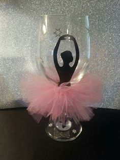 a wine glass with a ballerina silhouette on the bottom and pink tulle around it