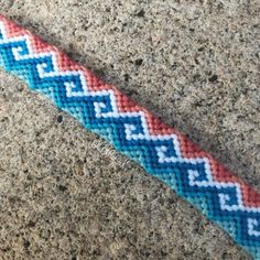 a blue and red bracelet sitting on top of a sidewalk