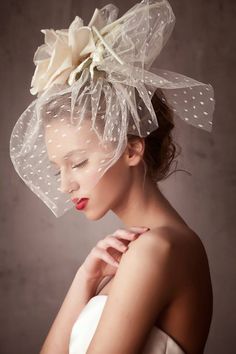 a woman wearing a veil with flowers on it's head and holding her hand under her chin