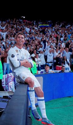 a man sitting on top of a bench in front of a crowd at a soccer game