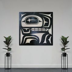 two potted plants sit in front of a painting on the wall