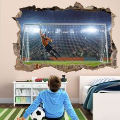 a boy is sitting on the floor with a soccer ball in front of his wall