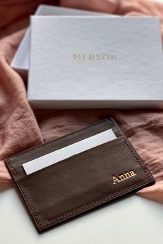 a card case sitting on top of a bed next to a pink blanket and a white box