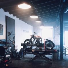 an old motorcycle is being worked on in a garage with other tools and equipment around it