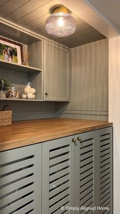 a kitchen with gray cabinets and wooden counter tops, along with a light hanging from the ceiling