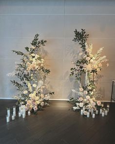 two tall vases with flowers and candles are on the floor next to each other