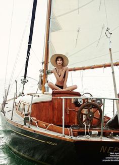 a woman sitting on the deck of a sailboat