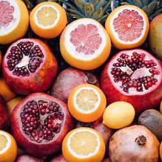 there are many different types of fruit on this table, including oranges and pomegranates