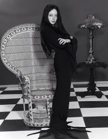 a black and white photo of a woman sitting on a chair in front of a lamp