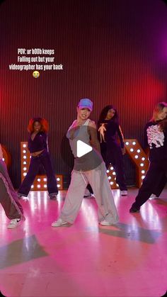 a group of young people dancing on top of a dance floor in front of neon lights