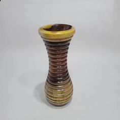 a small wooden vase sitting on top of a white table next to a black and yellow object