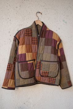 a jacket hanging on a wall with a hanger in front of it that is made out of patchwork fabric