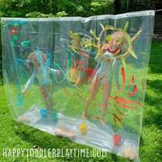 two children are playing in an inflatable ball on the grass with their hands