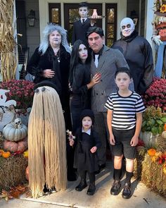 a family dressed up for halloween standing in front of a house with pumpkins and decorations