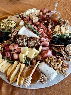 an assortment of cheeses, meats and nuts on a platter with honey