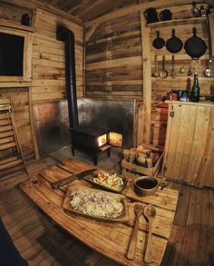 a wooden table topped with a pizza next to an open fire place in a log cabin