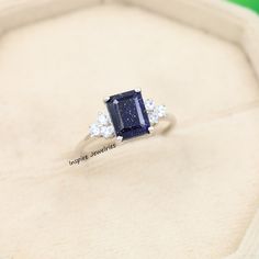 a blue and white diamond ring sitting on top of a box