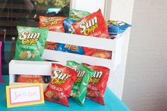 some chips are sitting on a table with a sign and candy bar in the background