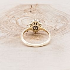 a yellow gold ring sitting on top of a tree stump in front of a white background