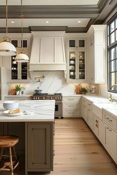 a large kitchen with white cabinets and wooden flooring is pictured in this image, there are two stools at the center of the island