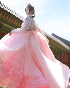 a woman in a pink dress is standing outside