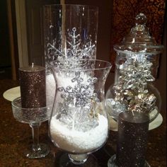 three wine glasses are sitting on a table with snow flakes and candles in them