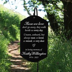 a sign that is on the side of a dirt road with trees in the background