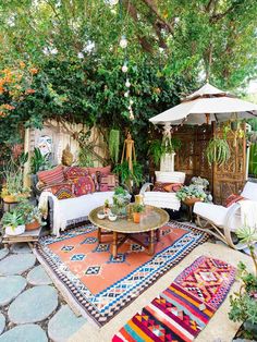 an outdoor living area with couches, tables and umbrellas in the middle of it