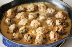 a blue bowl filled with meatballs and gravy on top of a table