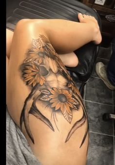 a woman with sunflowers tattoo on her thigh and leg sitting next to a black chair