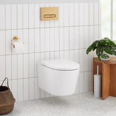 a white toilet sitting in a bathroom next to a wooden table and potted plant