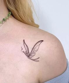 the back of a woman's shoulder with a small tattoo design on her left side