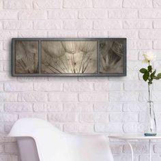 a white chair sitting in front of a brick wall with two pictures on the wall