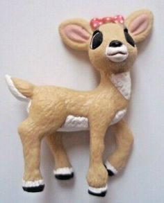 a toy deer with a bow on its head is hanging from a wall ornament