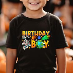 a young boy wearing a birthday shirt with an astronaut on it's chest and smiling at the camera