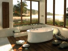 a large white bath tub sitting inside of a bathroom next to a wooden floor and windows