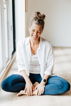 a woman is sitting on the floor smiling