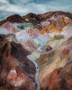 the mountains are covered in multicolored rocks and dirt, with a river running between them