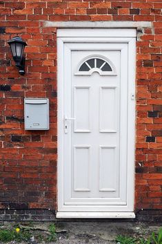 a brick wall with a white door and mailbox