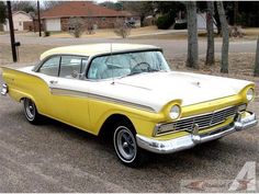 an old yellow and white car parked on the street