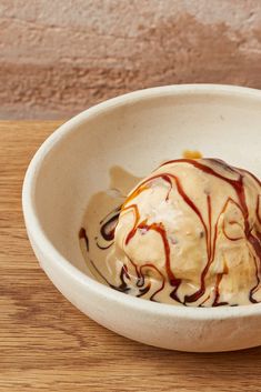 a white bowl filled with ice cream on top of a wooden table