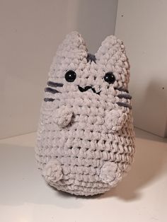 a crocheted cat sitting on top of a white table next to a wall