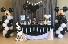 a mickey mouse themed birthday party with black, white and silver balloons on the table