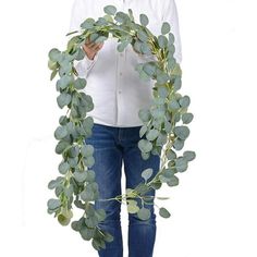 a woman holding a wreath made out of eucalyptus leaves