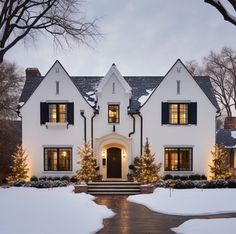 a white house with black shutters and christmas trees