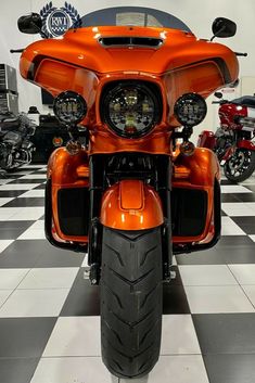 an orange motorcycle is parked on a checkered floor